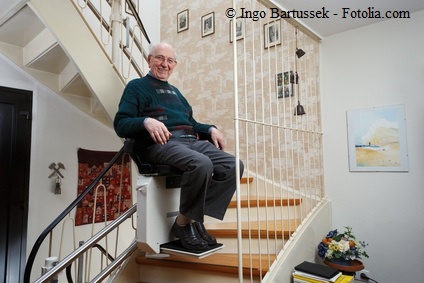 Pflegebedürftiger Senior fährt mit dem Treppenlift nach oben