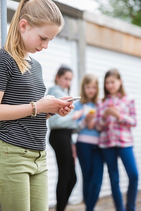 Handys können Kinder ablenken und so Druck aufbauen Kind mit Handy, Freundinnen im Hintergrund
