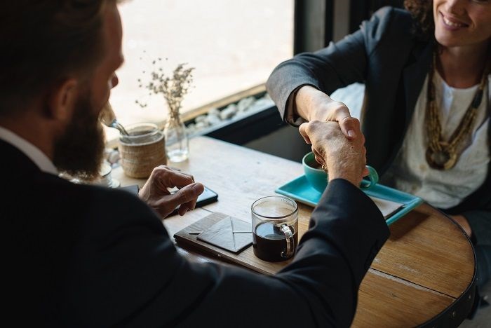 Ein Business-Lunch im richtigen Ambiente ist nachweislich eine der besten Methoden, um Vertrauen mit einem neuen Geschäftspartner aufzubauen. Mann und Frau am Tisch, geben sich die Hand