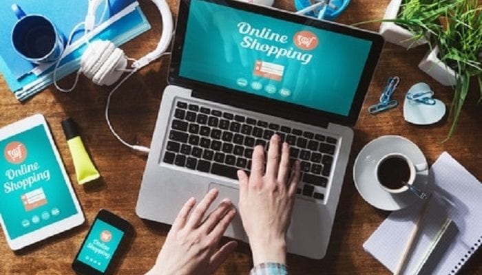 Mann tippt am Laptop in einem Online Shopping Portal