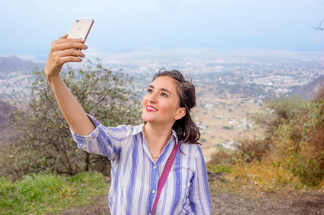 Frau steht auf einem Berg und macht ein Selfie von sich