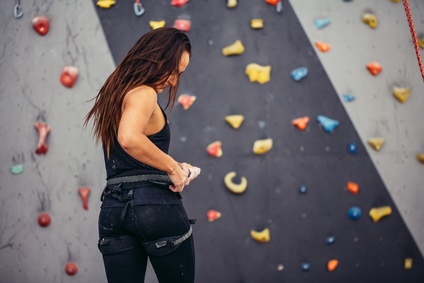 Frau steht vor einer Kletterwand