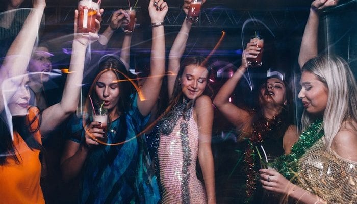 Frauen tanzen mit Cocktails auf einer Party
