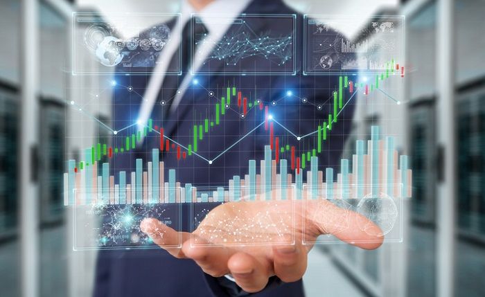 Um den richtigen Broker zu finden, der mehr aus Ihrem Geld macht, bedarf es einiger Überlegungen Mann steht vor Tafel mit Kursverläufen