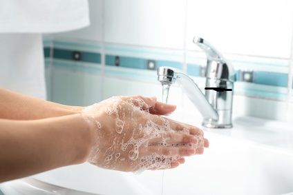 Frau wascht sich die Hände über einem Waschbecken