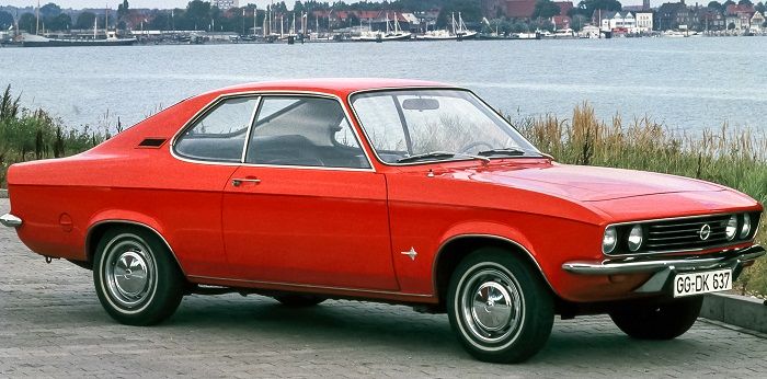 Ein roter Opel Manta Baujahr 1971 steht vor einem Fluss