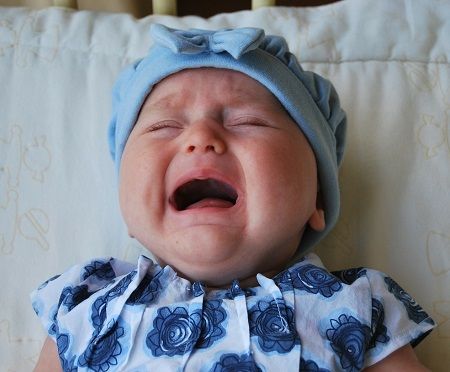 Baby liegt weinend im Bett