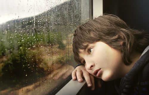 Junge sitzt traurig an einem Zugfenster