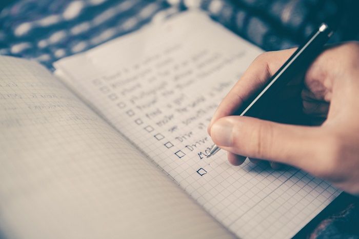 eine gut geplante Autoreise verhindert so manchen Stress checkliste wird auf einem karierten Block geschrieben