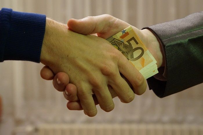 Bei finanziellen Engpässen können Minikredite kurzfristig sehr hilfreich sei Mann gibt per Handschlag jemandem Geld