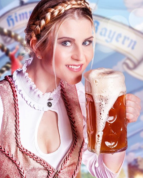 Frau im Dirndl hebt eine Mass Bier zum trinken an