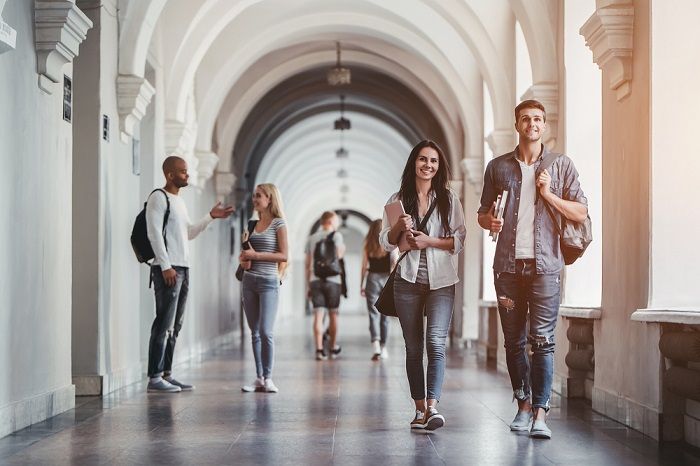 Bei manchen nicht bestandenen Prüfungen kann die Prüfungsanfechtung eine große Hilfe sein Junge Leute laufen im Gang einer Uni