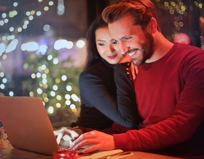Ein Paar sitzt in der Weihnachtszeit vor dem Laptop 