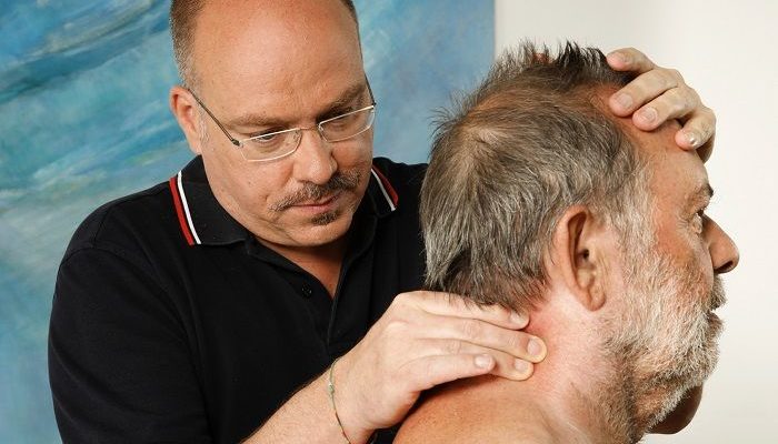 Ein Therapeut behandelt einen Patienten im Halswirbelbereich