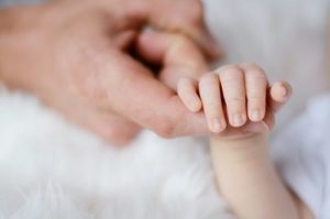 Eine Babyhand umklammert den Zeigefinger seiner Mutter