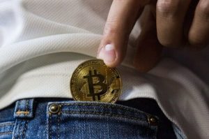 Frau steckt einen Bitcoin in Ihre kleine Jeanstasche