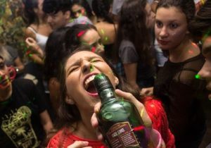 Jugendliche feiern, ein Mädchen trinkt harten Alkohol aus einer großen Flasche