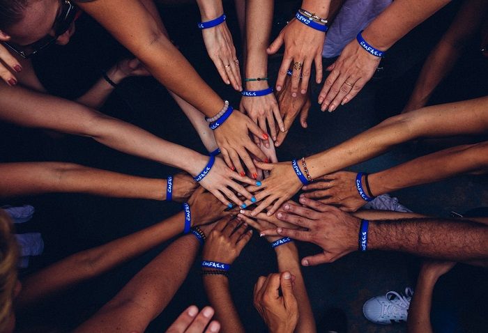 Verschiedene Menschen legen, zum Zeichen der Solidarität, die Hände übereinander