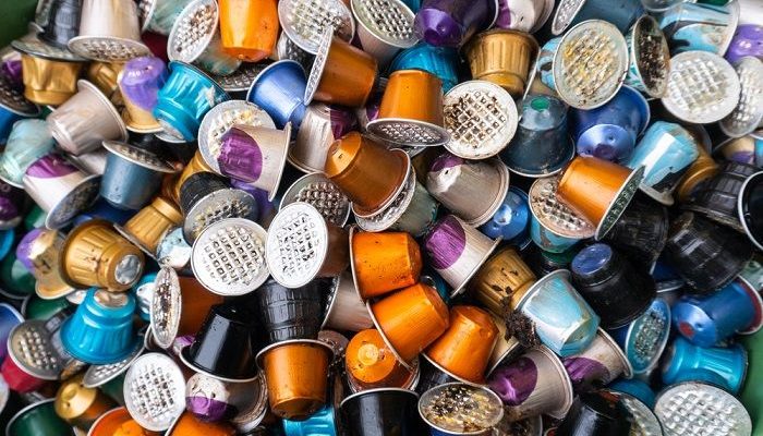 Viele Kaffekapseln in verschiedensten Farben liegen in einer Mülltonne