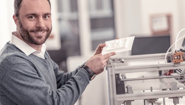 Mann zeigt an einem 3D Drucker ein ausgedrucktes Modell