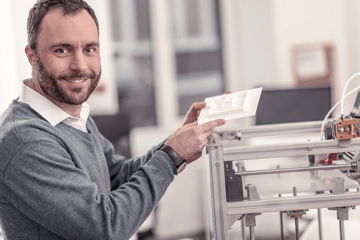 Mann zeigt an einem 3D Drucker ein ausgedrucktes Modell