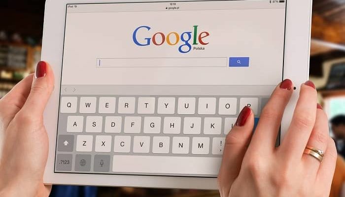Frau hält ein Tablet in der Hand, die Google Suchmaske ist zu sehen