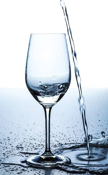 Wasser wird neben ein Glas gegossen