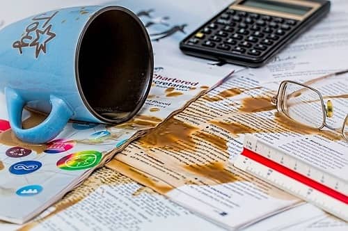 Umgekippte Tasse Kaffee über wichtigen beruflichen Unterlagen