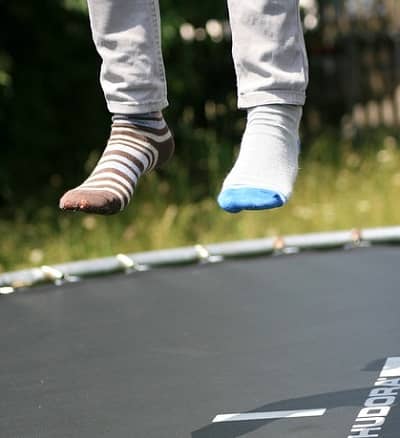 Zwei füße mit unterschiedlichen Socken, springen im Garten Trampolin