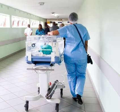 Eine Krankenschwester schiebt ein Krankenbett durch einen Krankenhausflur