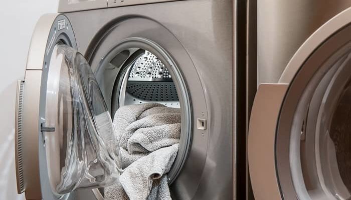 Eine Waschmaschine steht geöffnet mit einem Handtuch darin im Raum