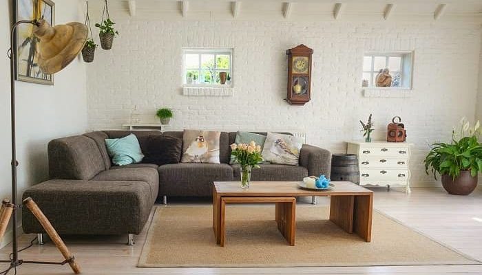 Ein skandinavischer Wohnraum, braune Couch, beiger Teppich und Boden sowie Naturmaterialien