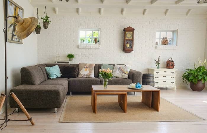 Ein skandinavischer Wohnraum, braune Couch, beiger Teppich und Boden sowie Naturmaterialien