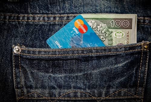 In der Gesäßtasche einer Jeans steckt Bargeld und eine Master Card