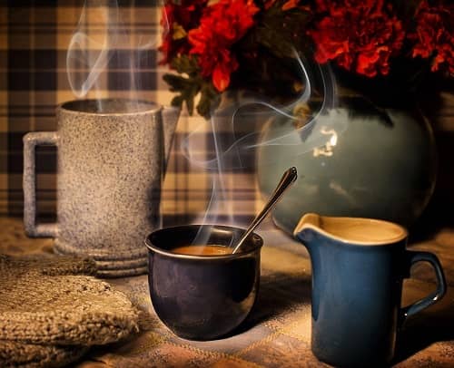 Gemütlicher Küchentisch mit Kaffeetassen und einer Vase mit roten Blumen