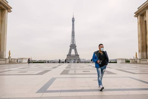 Ein Urlauber geht über einen großen Platz im Hintergrund sieht man den Eiffelturm