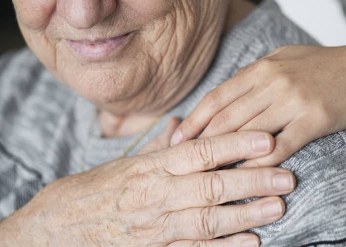 Ältere Frau legt Ihre Hand auf die Hand Ihrer Pflegerin