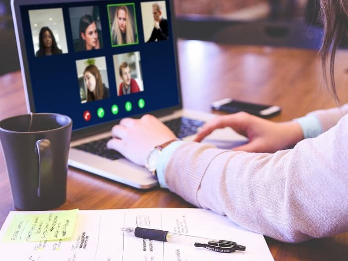 Frau sitzt vor einem Laptop und hat gerade eine Videokonferenz mit 5 Personen