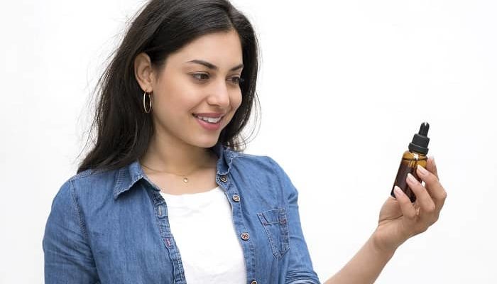 Junge Frau hält ein Fläschchen in der Hand