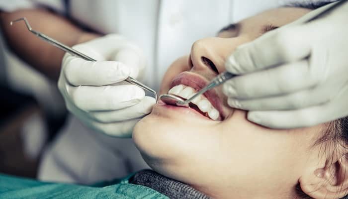 Eine junge Frau wird vom Zahnarzt in der Praxis behandelt