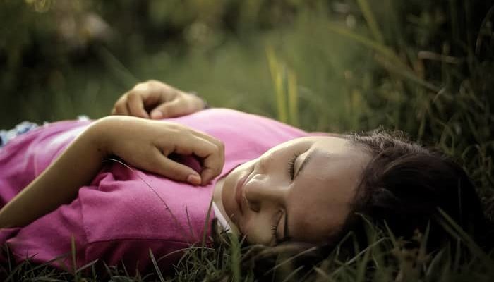 Frau liegt entspannt im Gras und schläft