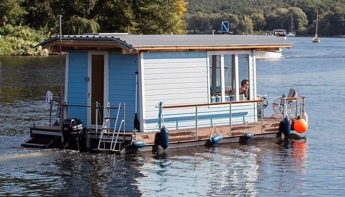 Ein weiß/blaues Hausboot schippert über einen See