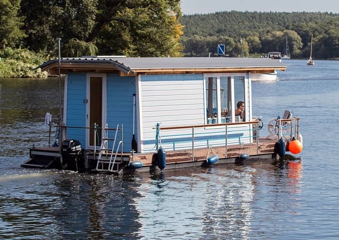 Ein weiß/blaues Hausboot schippert über einen See