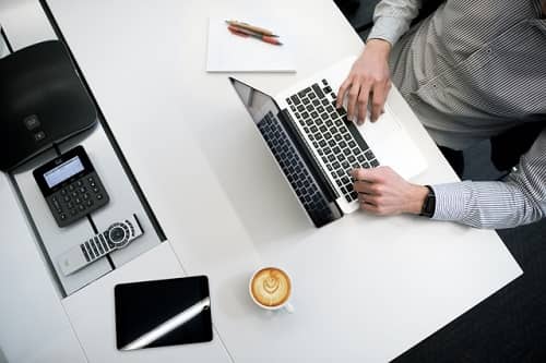 Ein Mann sitzt mit einem Kaffee vor seinem Laptop