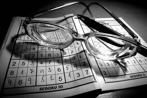 Ein Sudoku Heft liegt auf dem Tisch, darauf eine Brille und ein Kugelschreiber