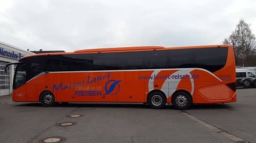 Ein großer Oranger Bus mit großen Werbebeschriftungen