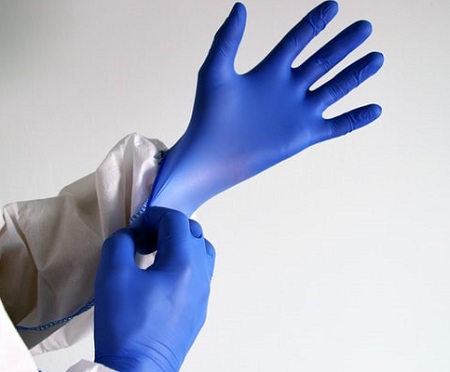 Eine Person zieht sich gerade blaue Hygiene Handschuhe über