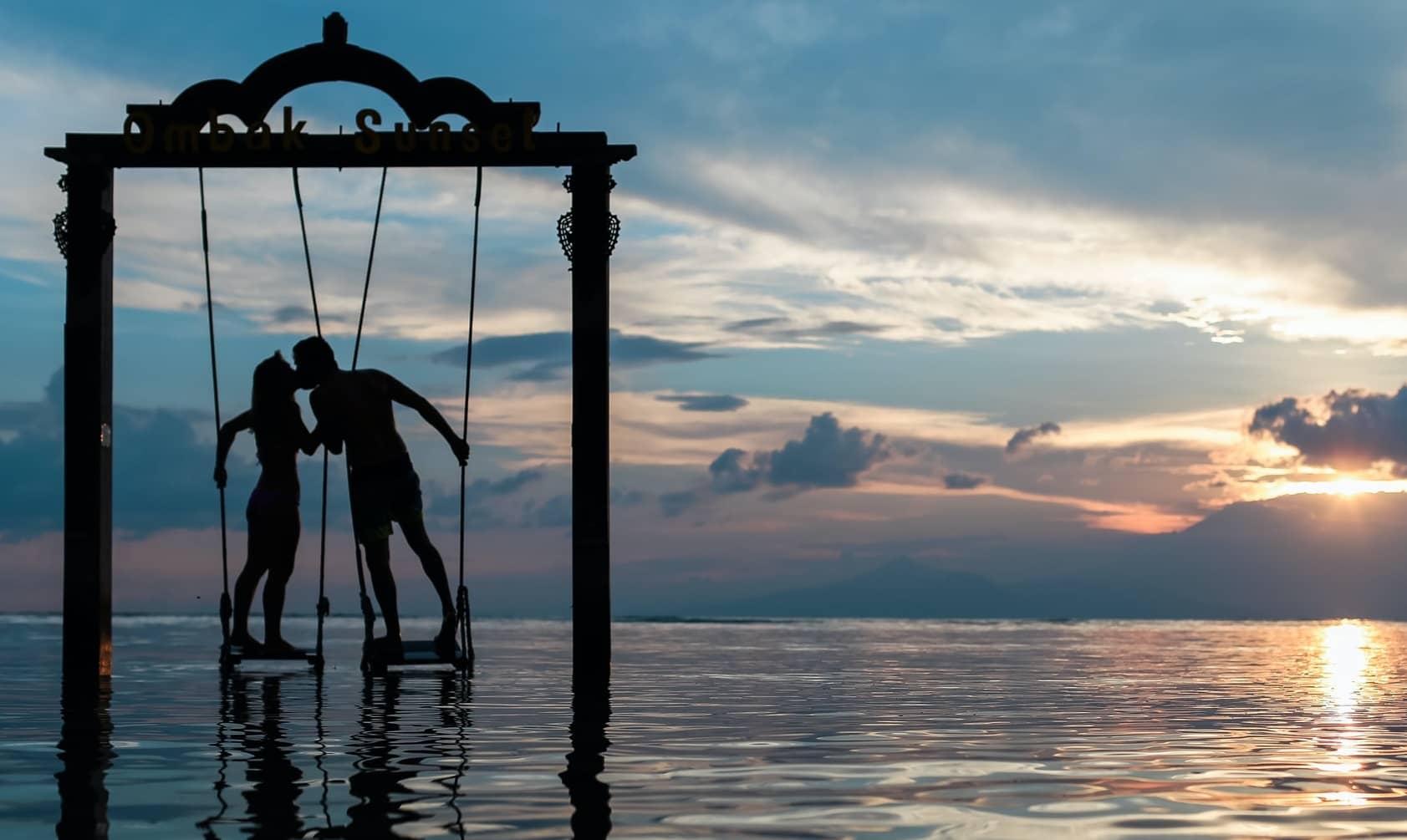 Fantasie, zwei Liebende unter einem Hochzeitsbogen direkt im Meer bei einem romantischen Sonnenuntergang