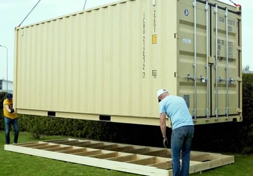 Ein großer Container wird gerade auf ein Schraubfundament aus Holz aufgestellt