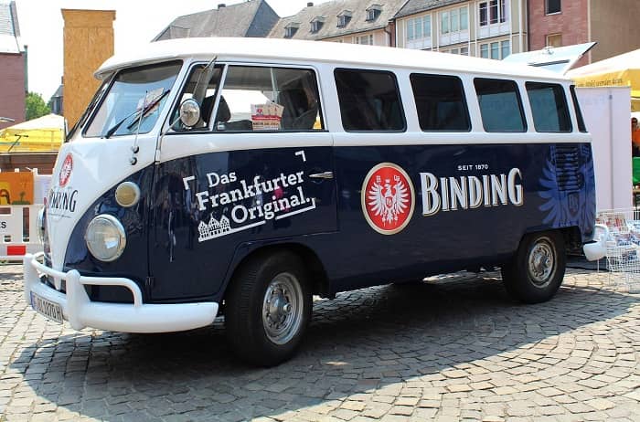 Ein dunkelblau/weißer VW-Bus mit großer Binding Bier Werbung